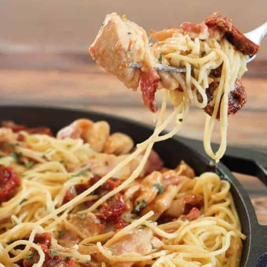 Tuscan chicken pasta on fork over pan