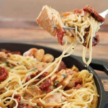Tuscan chicken pasta on fork over pan