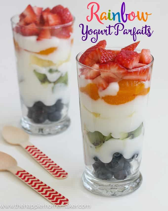 A close up of two glasses of rainbow yogurt parfaits topped with strawberries