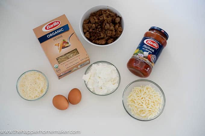 An above picture of the ingredients used to make baked penne rigate including cheese, eggs, pasta, and tomato sauce