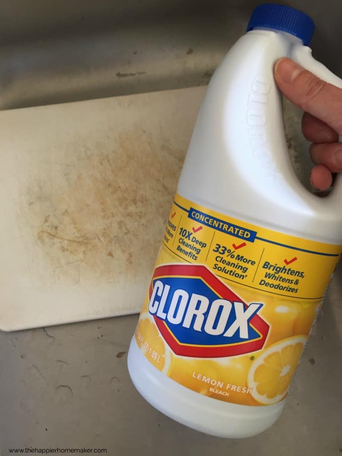 A close up of Clorox bleach with a dirty plastic cutting board in the background