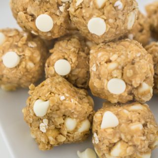 no bake peanut butter balls with oats and white chocolate chips stacked on white plate