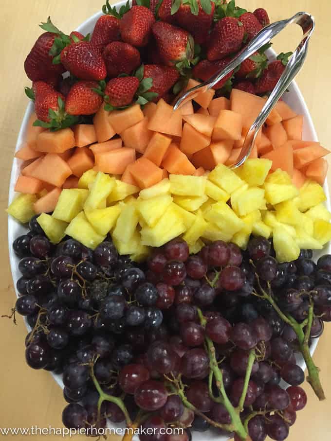 A plate of cut fresh fruit including melon, pineapple, strawberries and grapes