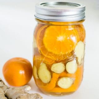 A mason jar of orange and ginger simmer pot with an orange next to it