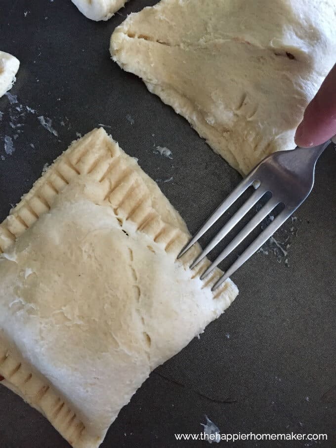 An in-process picture of preparing sloppy joe pockets wrapped up and a fork making the edges patterned 