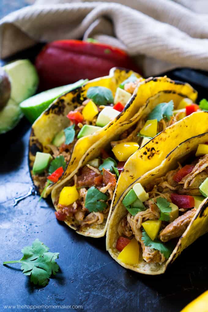 Three soft chicken tacos topped with avocados and peppers 