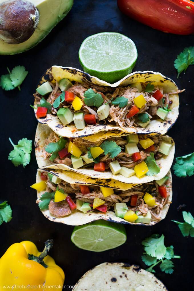Three soft chicken tacos topped with avocados and peppers 
