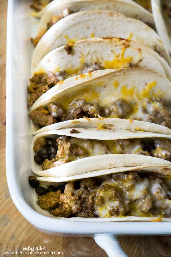 A tray of oven baked tacos with meat and cheese