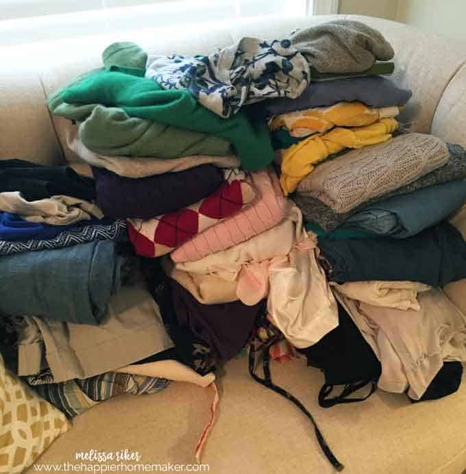 Several piles of women's clothes on a small sofa