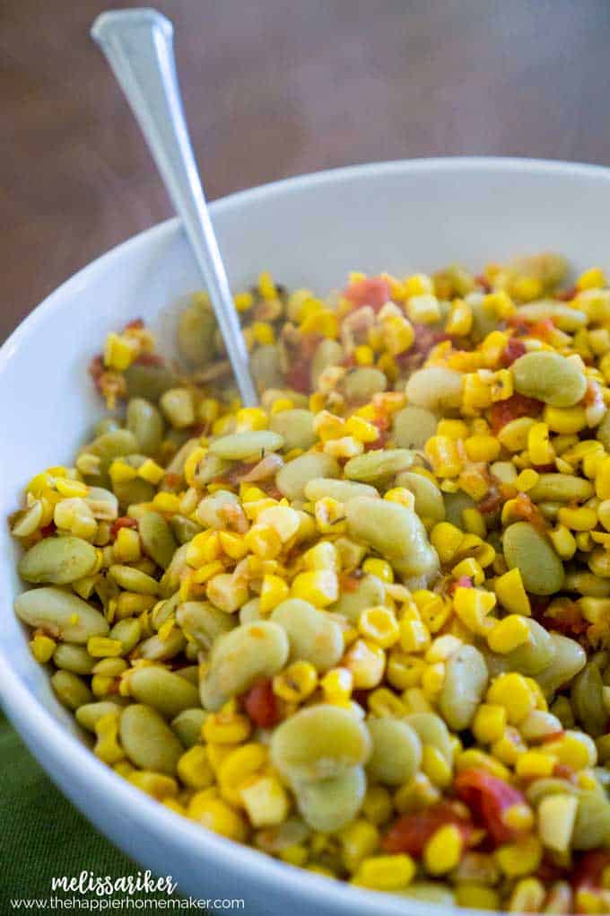 succotash in white bowl with spoon