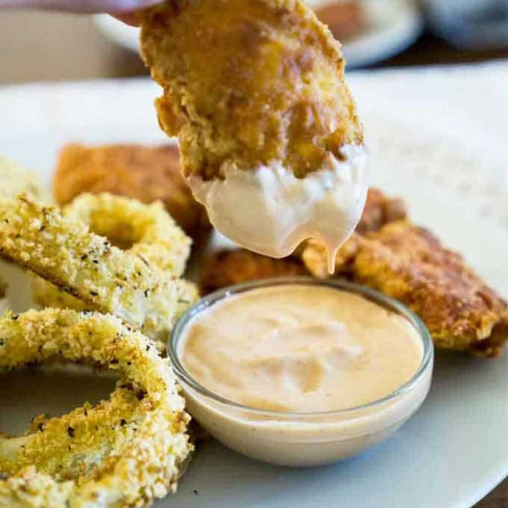 chicken finger dipping in copycat zax sauce