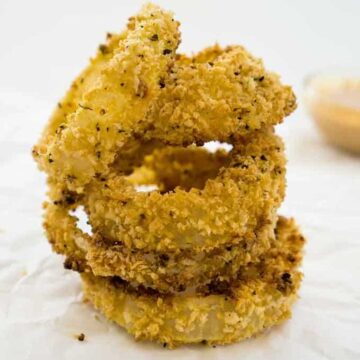 stack of crispy baked onion rings on parchment paper