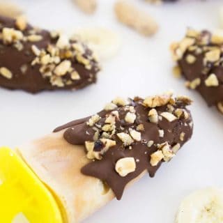A close up of chocolate chunky monkey pops coevred with crushed peanut covering