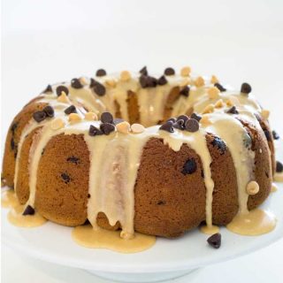 A peanut butter chocolate chip cake on a plate topped with peanut butter glaze and chocolate chips