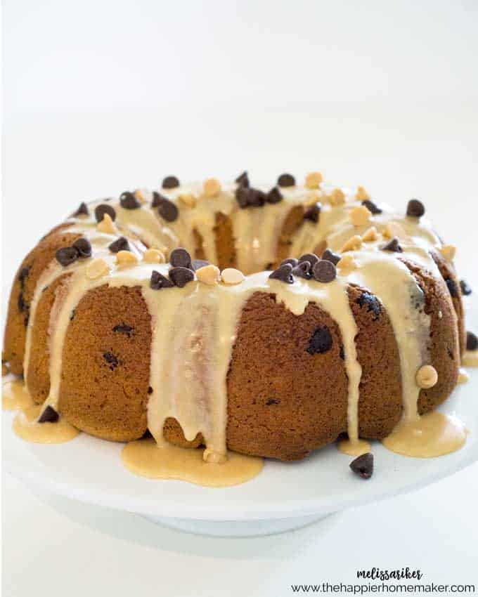 A peanut butter chocolate chip cake on a plate topped with peanut butter glaze and chocolate chips