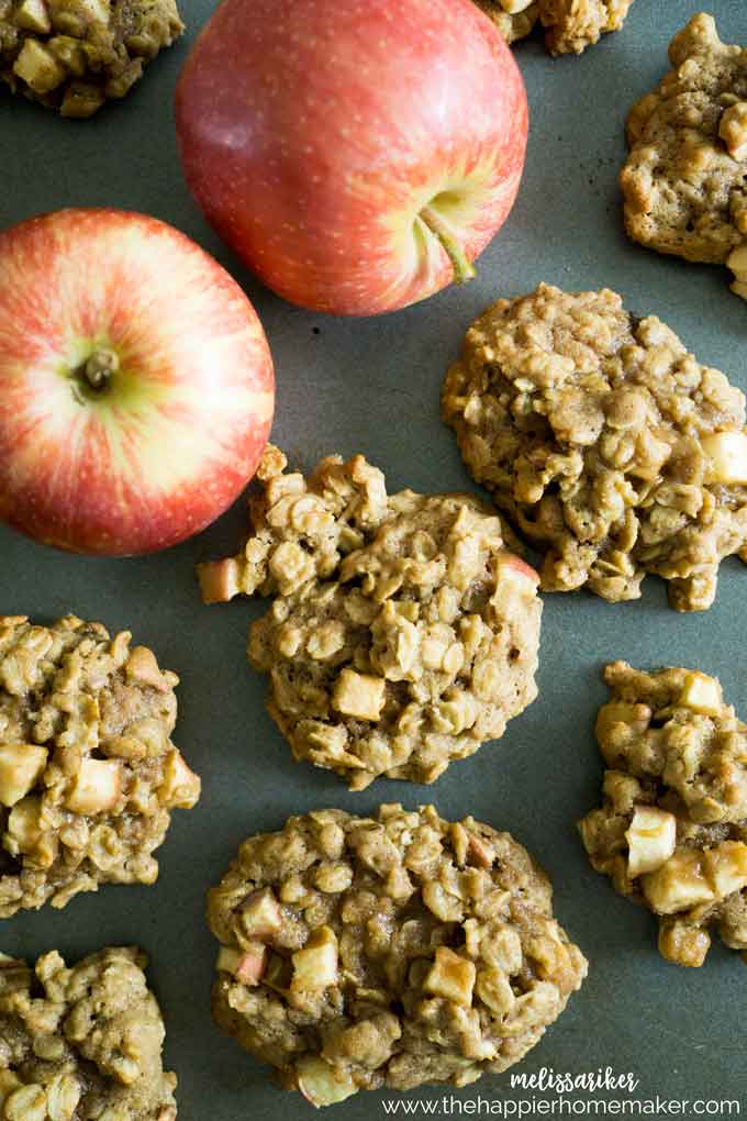 A close up of cinnamon apple oatmeal cookies with two apples