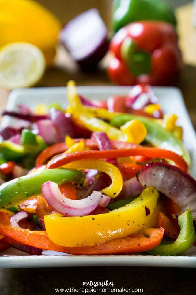 Roasted red, yellow, and green bell peppers with red onion on a white plate