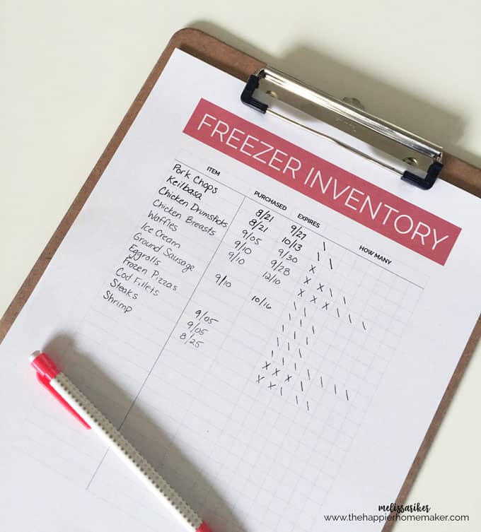 A close up of a piece of paper titled "Freezer Inventory" on a clipboard with a pen on it