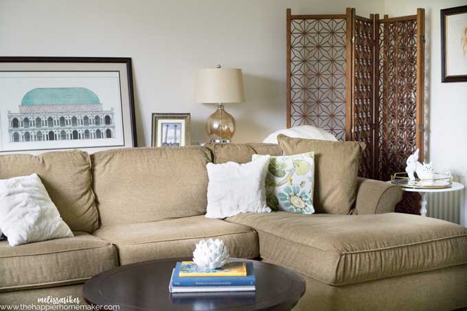 A green sofa with a lamp, coffee table and art