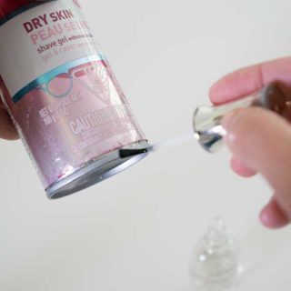 Someone applying clear nail polish to the bottom of a metal shaving cream can to prevent rust rings in the shower