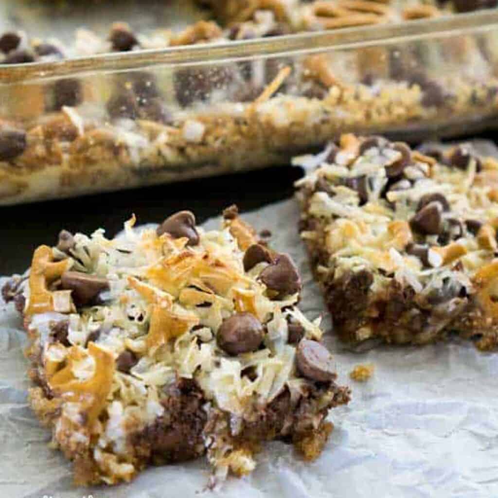 two caramel pretzel magic bars on parchment paper