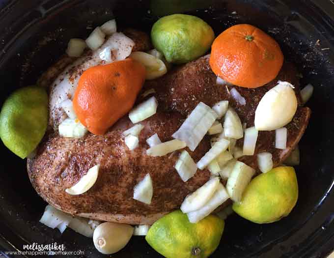 Slow cooker pork carnitas topped with onion, oranges and limes