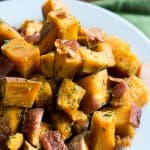 cooked diced sweet potatoes with bacon and parsley on white plate