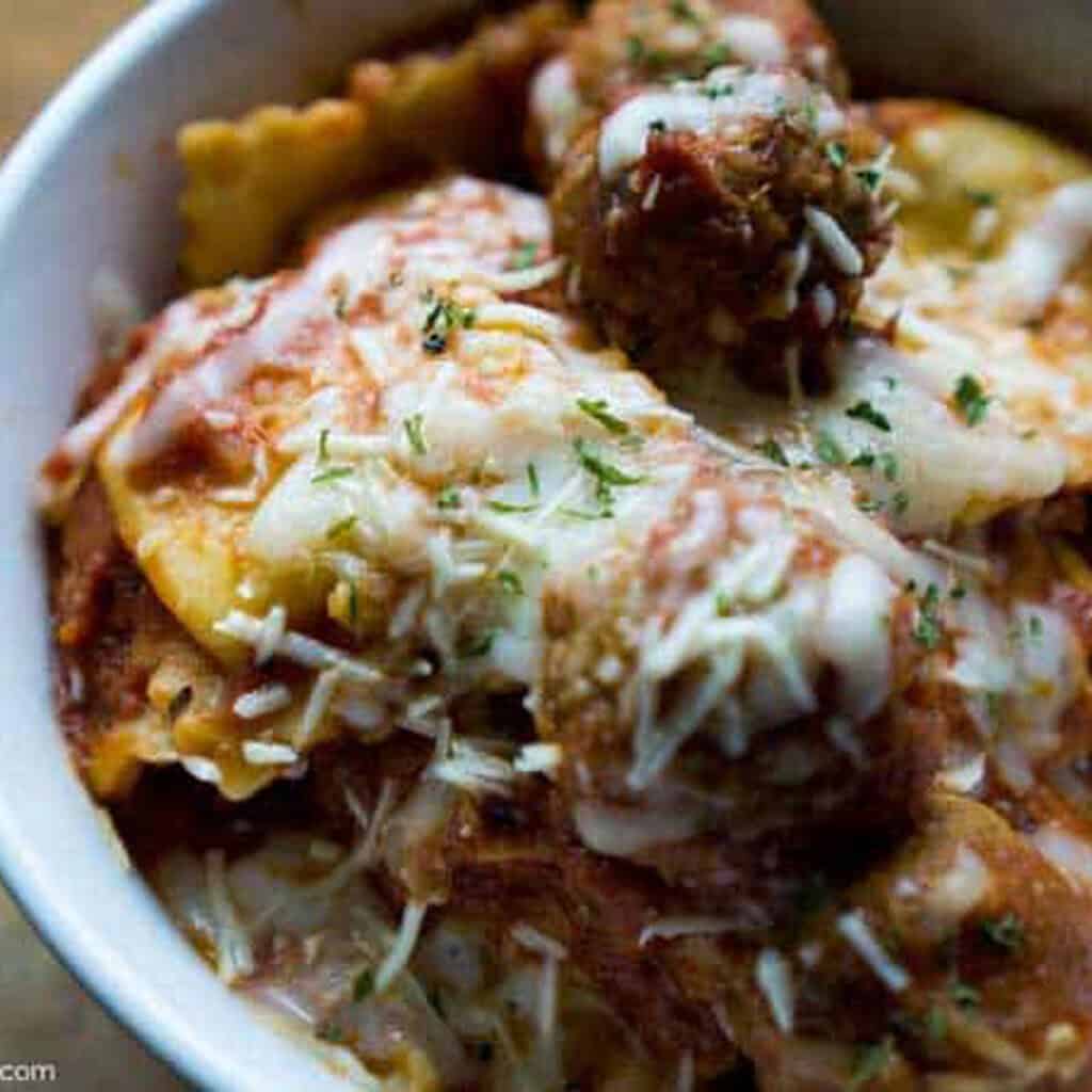 close up of ravioli and meatballs in a white bowl