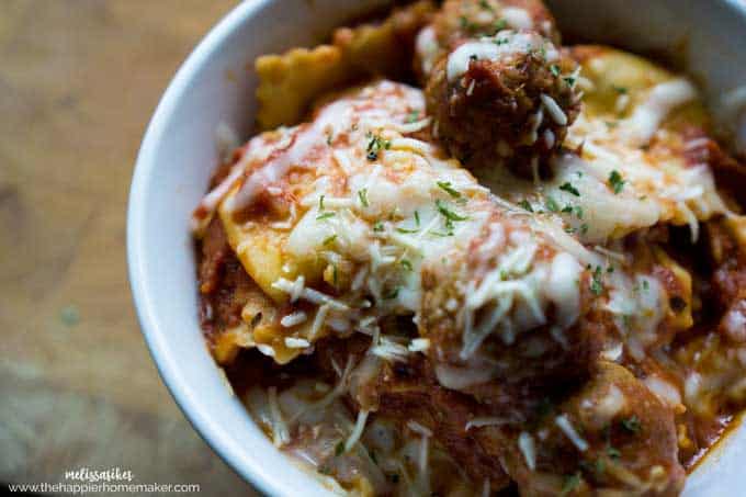 A bowl of slow cooker ravioli with meatballs topped with melted cheese