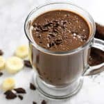 A chocolate coffee smoothie on a table, with Chocolate and banana slices