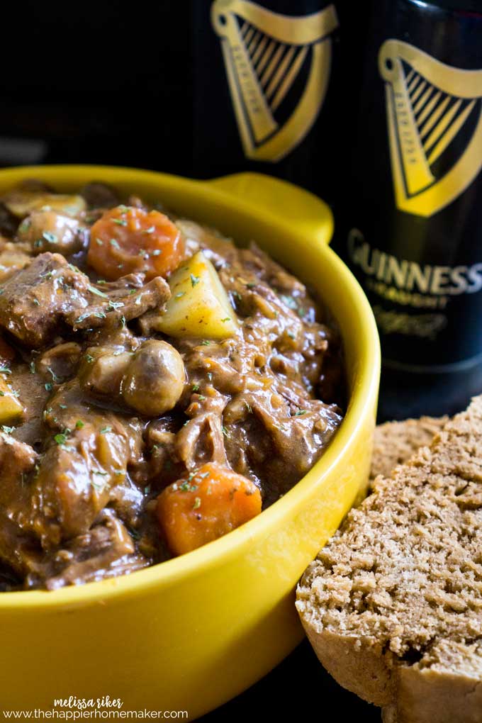 A yellow bowl full of Guinness Irish Beef Stew with two Guinness cans in the background