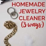 A brass bracelet and platinum wedding rings on white paper with the words "Homemade Jewelry Cleaner (3 ways)"
