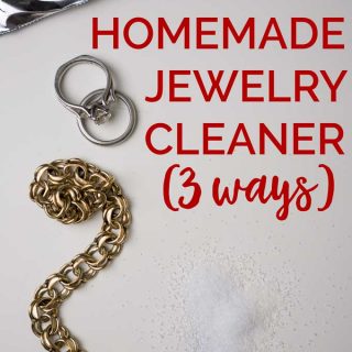 A brass bracelet and platinum wedding rings on white paper with the words "Homemade Jewelry Cleaner (3 ways)"
