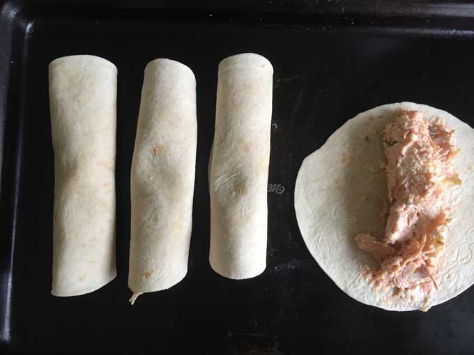 A pan of Chicken Taquitos with three ready to cook and one partially completed 