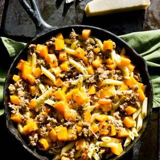 A cast iron pan filled with butternut squash and sausage penne
