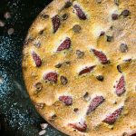 A close up of baked strawberry chocolate chip cake on a dark table