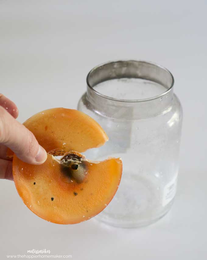 A close up of a person holding the orange wax from the bottom of the glass candle jar