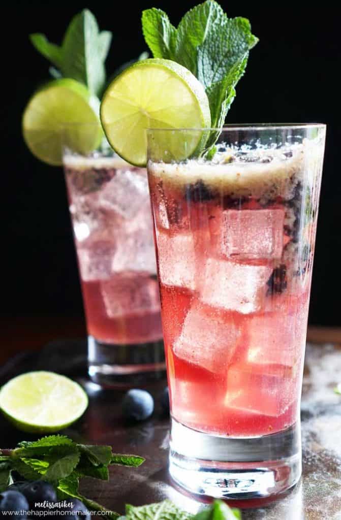 two blueberry mojitos garnished with lime 