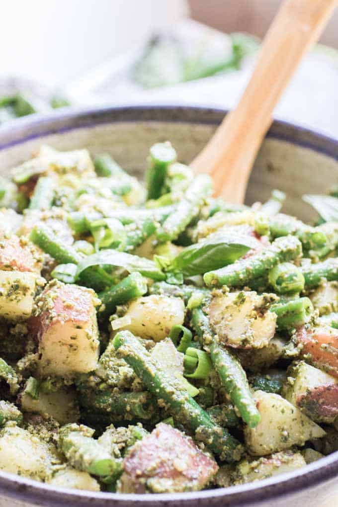 pesto potato salad with green beans and wooden spoon.