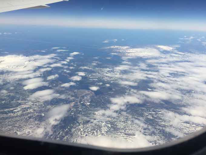 A picture of the earth taken from a plane showing clouds and water.