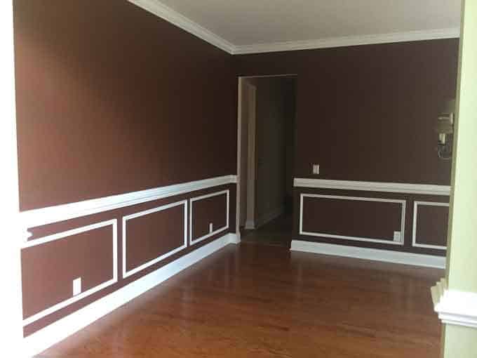 An empty room painted dark brown with white molding trim