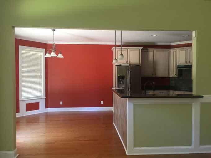 A kitchen with wooden cabinets, red walls and green walls in foreground