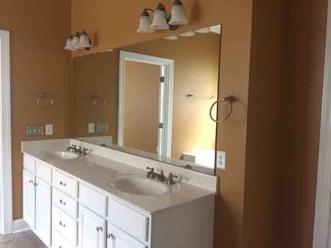 A bathroom with two sinks, a large mirror and brown wall color