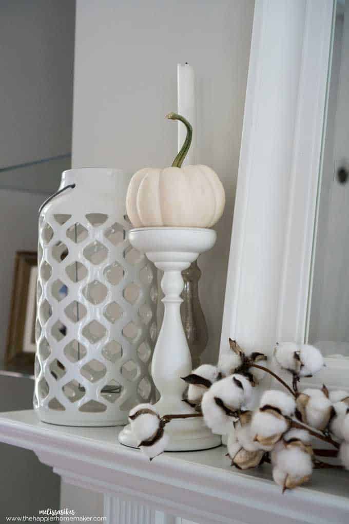 A close up of a white pumpkin and cotton on the side of a mantel