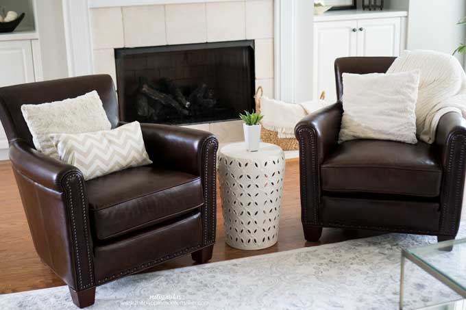 A close up of two leather chairs with a white side table and small plant