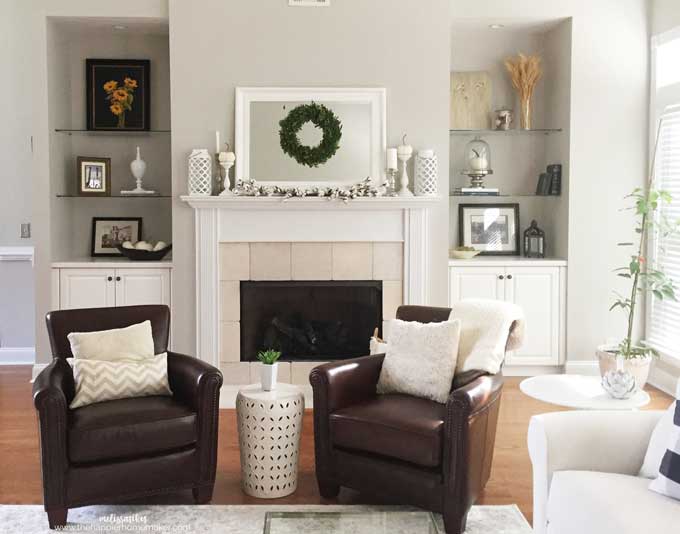 Two leather chairs sitting in front of a fireplace with a white mantel