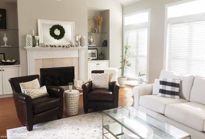 A living room with white sofa, two leather chairs and a glass coffee table