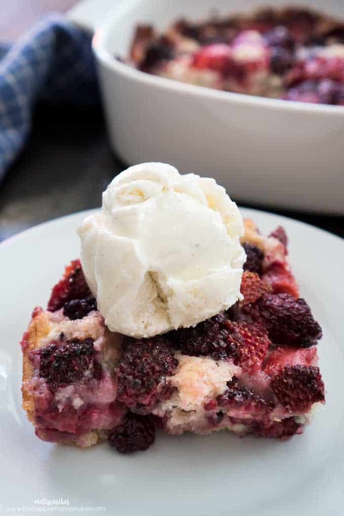 slice of berry cobbler on a white plate topped with ice cream