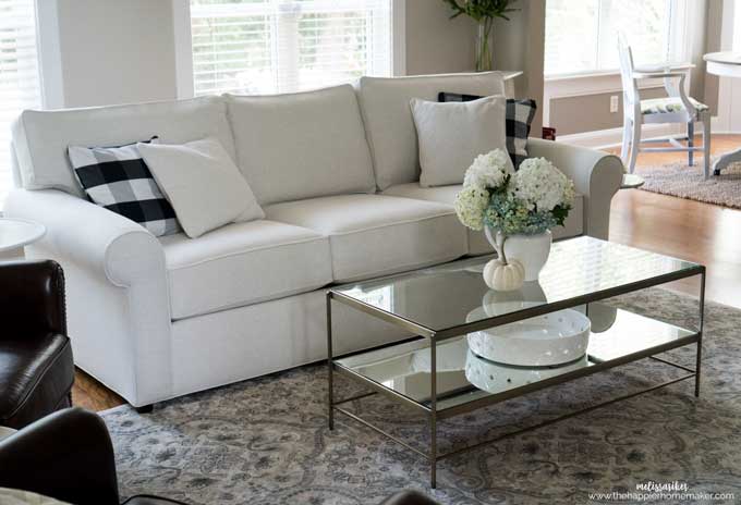 A white sofa with glass coffee table on a silk pattern rug
