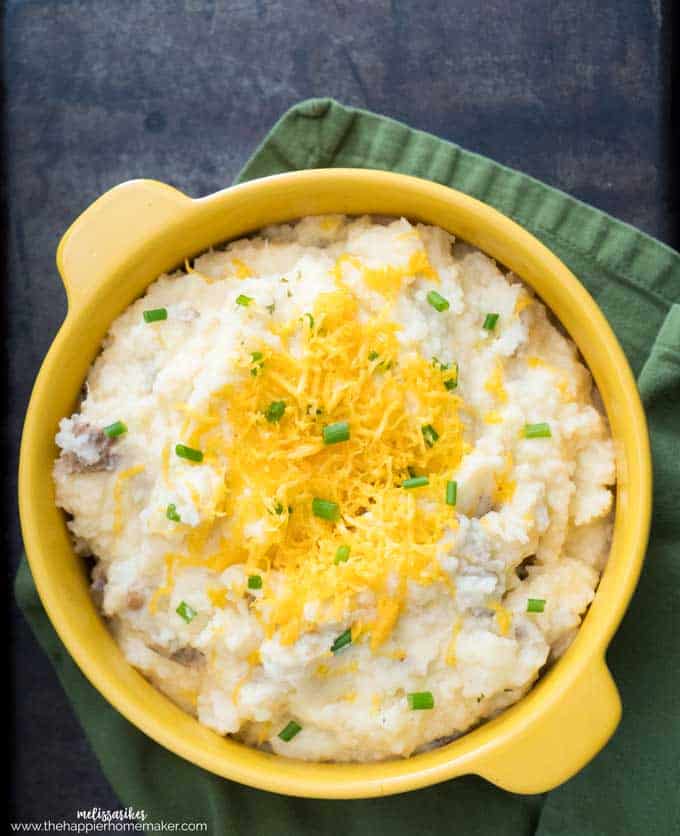 A top view of cheddar cheese mashed potatoes topped with chives and cheese